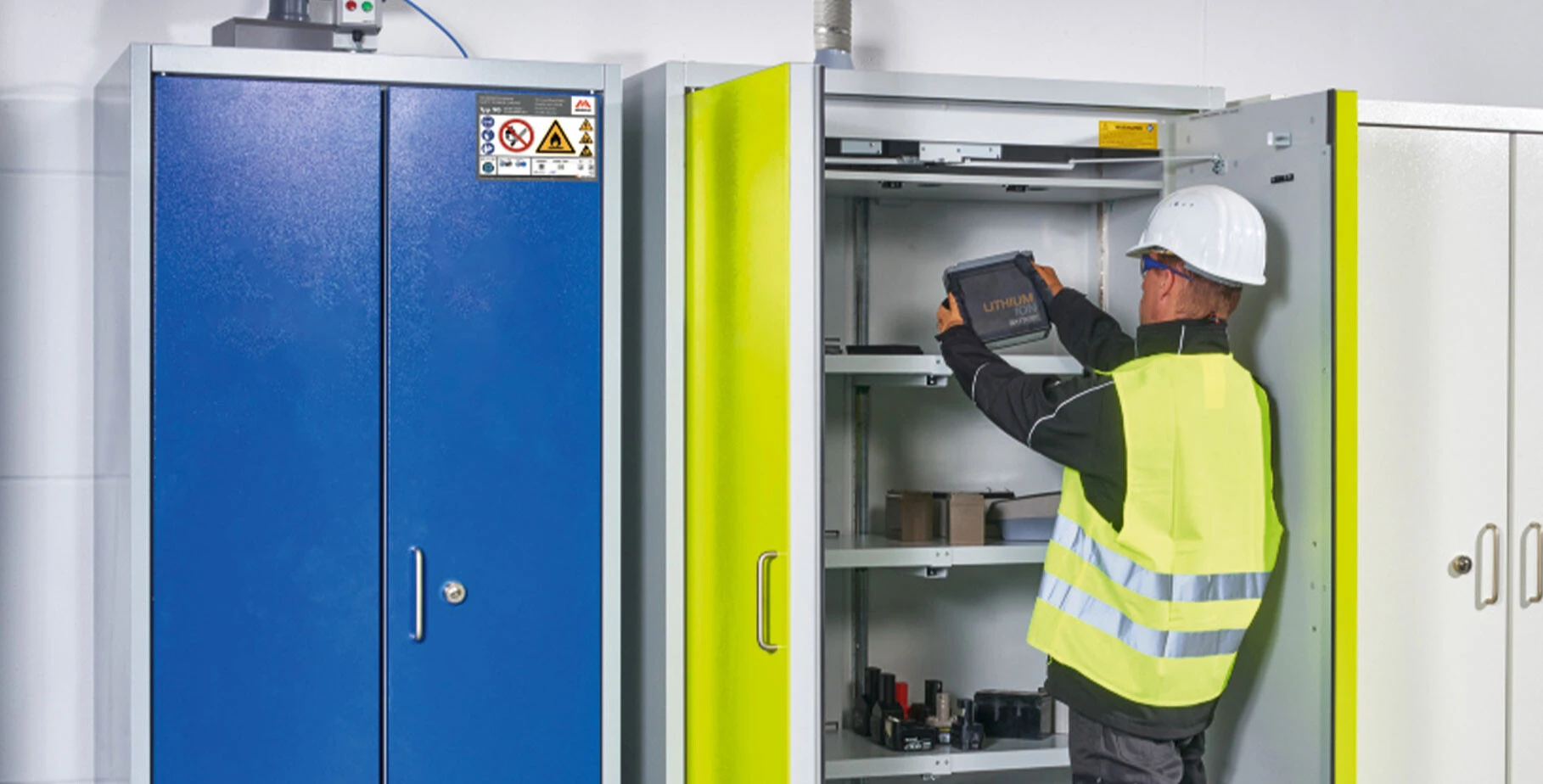 Arbeiter in Schutzausrüstung greift nach einem Behälter in einem geöffneten Aufbewahrungsschrank.