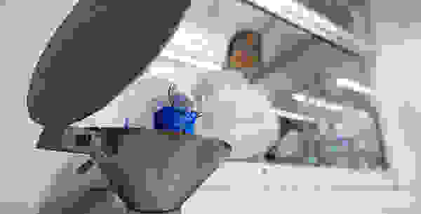 Eine Wissenschaftlerin gießt eine blaue Flüssigkeit aus einem Glasbehälter in einen Metalltrichter.