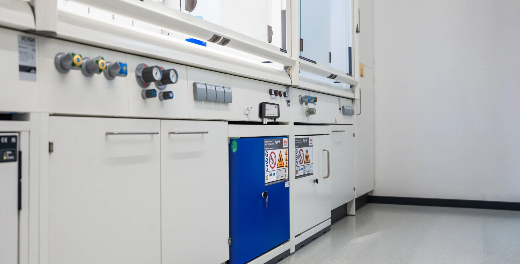 Laboratoryarbeitsplatz mit verschiedenen Reglern, Druckanzeigen und einem blauen Sicherheitsfach.