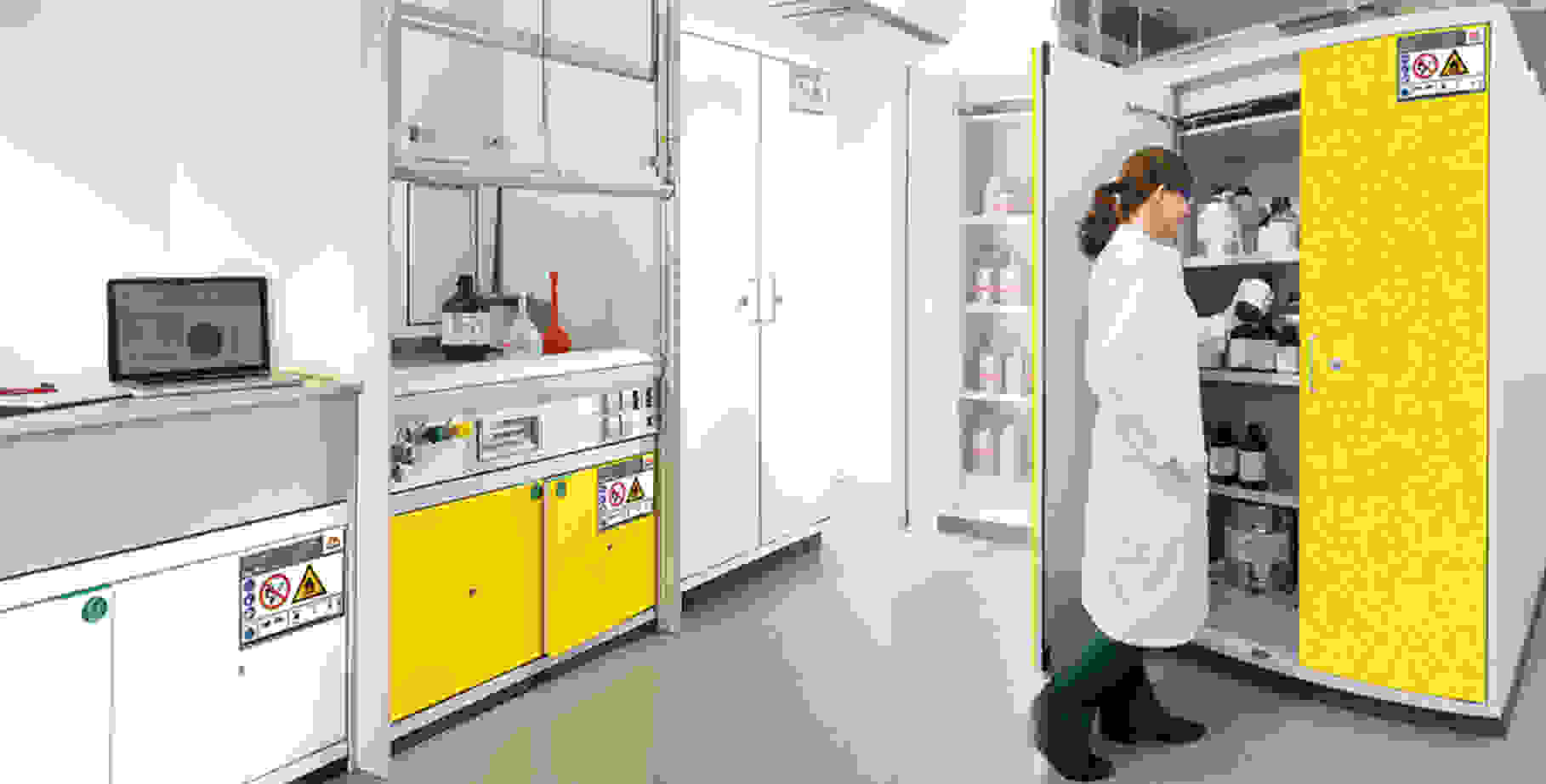 Laborszene mit einer Person in einem weißen Kittel, die Chemikalien aus einem gelben Schrank entnimmt. Hintergrund zeigt Laborausrüstung und einen Laptop.