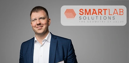 Portrait d'un homme souriant en costume avec le logo de SmartLab Solutions en arri&egrave;re-plan.