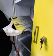 Une personne portant des gants retire un accumulateur d'une armoire &agrave; porte jaune.