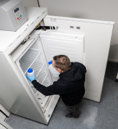 Une personne se tient devant un cong&eacute;lateur ouvert et tient deux bouteilles.
