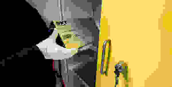 Une personne portant des gants blancs tient un accumulateur lithium-ion et le place dans une armoire jaune.