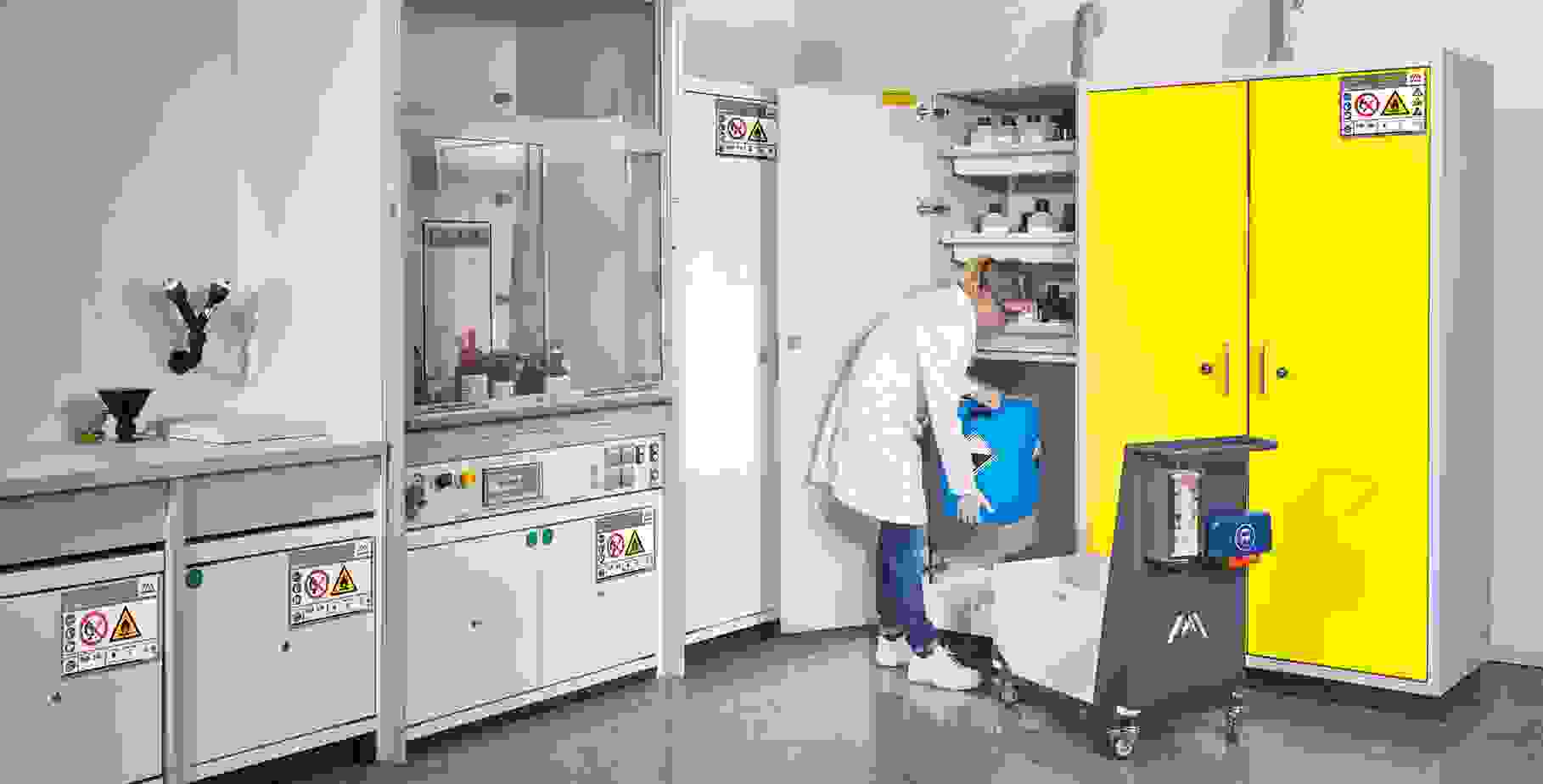 Laboratoire avec une personne en blouse de laboratoire blanche qui place un récipient bleu dans une armoire portant des avertissements. À l'arrière-plan, d'autres meubles de laboratoire et aménagements sont visibles.