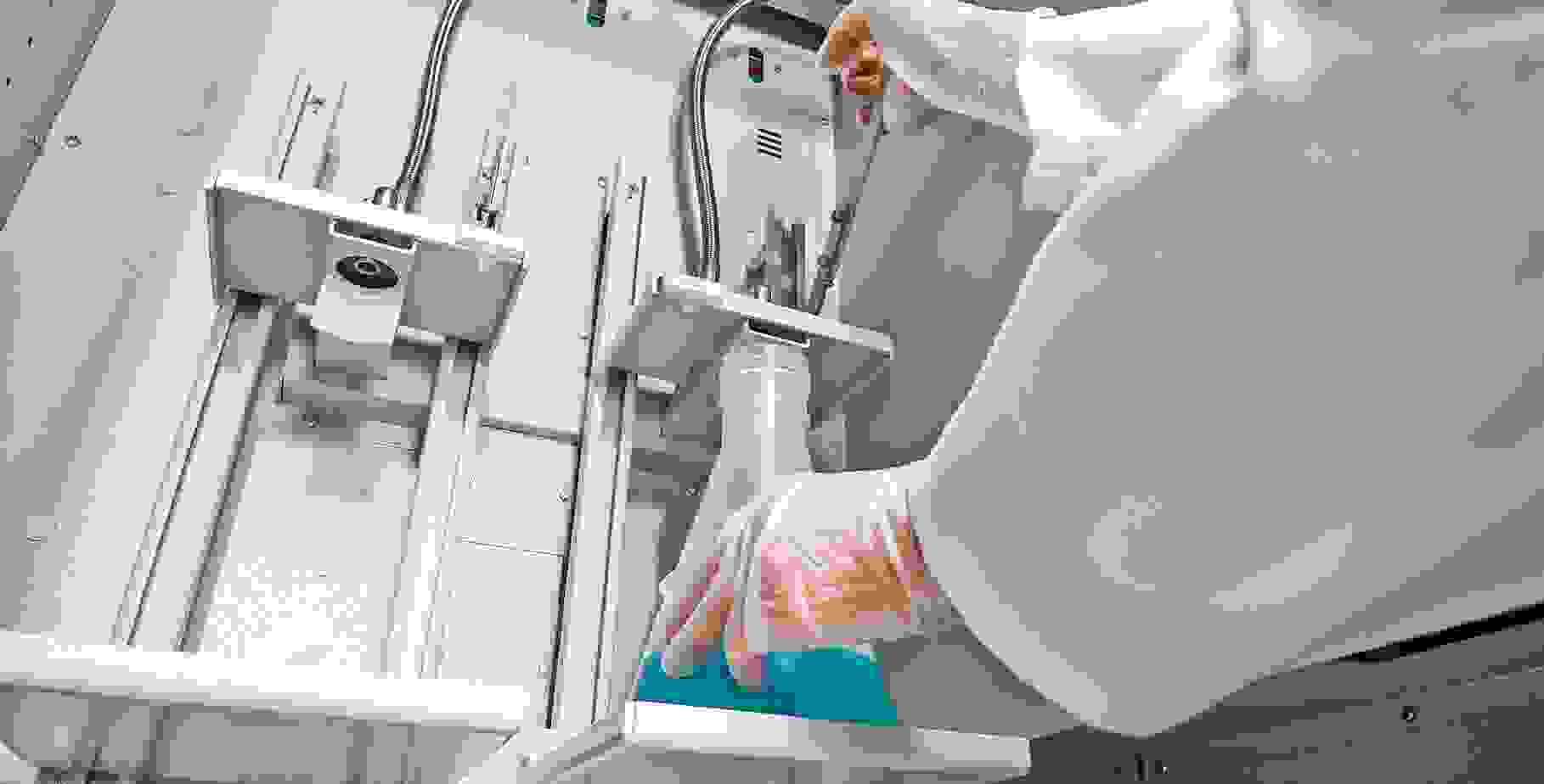 Un technicien de laboratoire tient un flacon Erlenmeyer contenant un liquide bleu dans un appareil comportant plusieurs tuyaux.