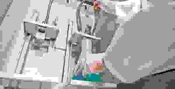 Un technicien de laboratoire tient un flacon Erlenmeyer contenant un liquide bleu dans un appareil comportant plusieurs tuyaux.