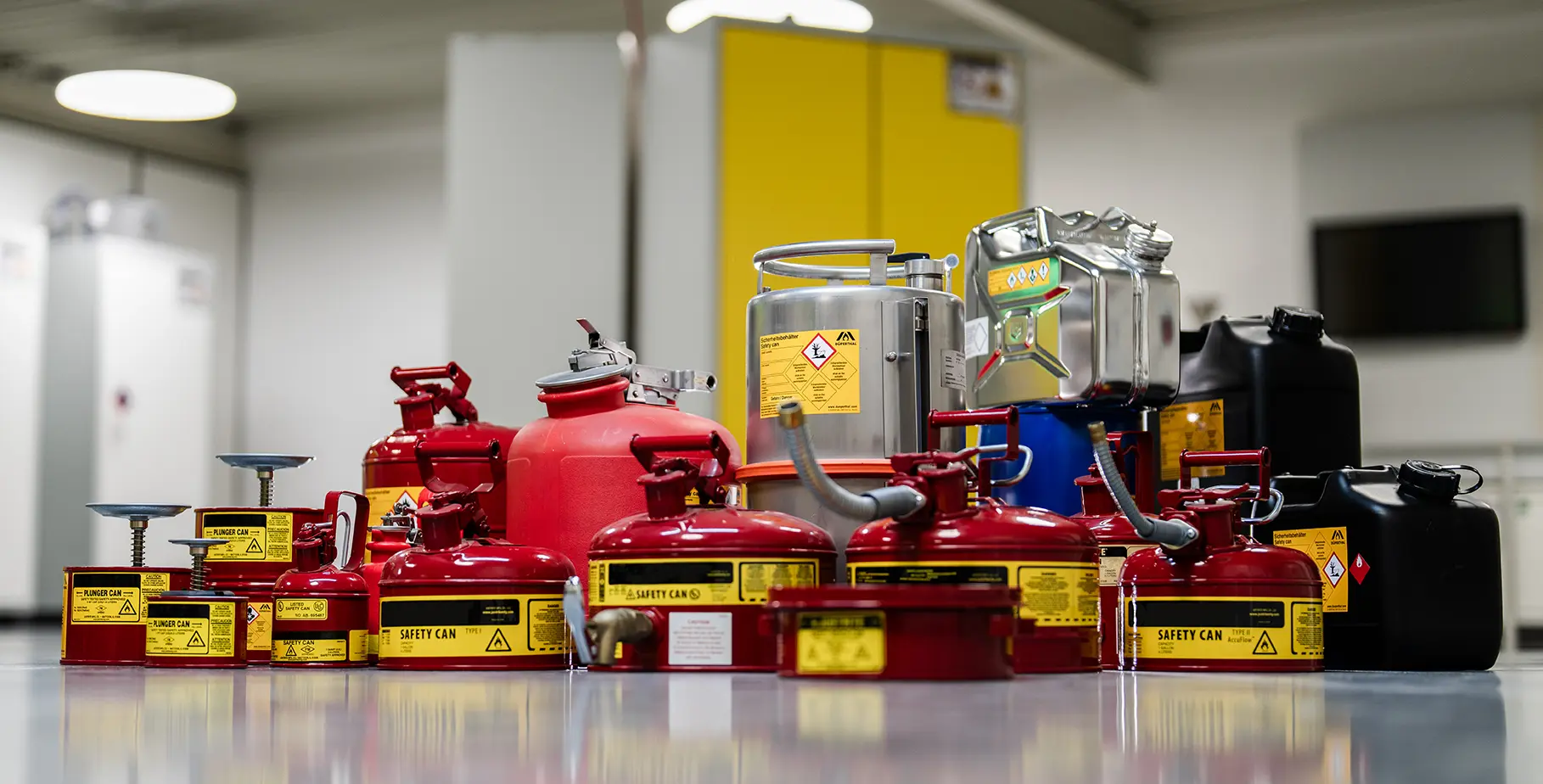 Une disposition de différents Récipients de sécurité, principalement en rouge, pour le stockage de liquides, avec des avertissements et des étiquettes.