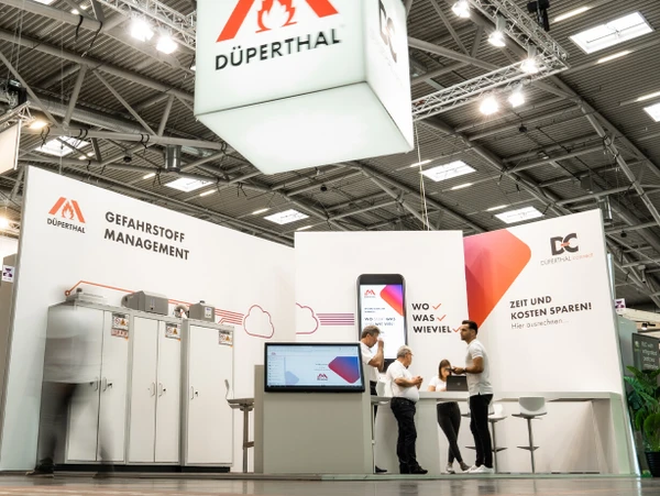 Stand de DÜPERTHAL axé sur la gestion des substances dangereuses, un écran numérique et plusieurs visiteurs.
